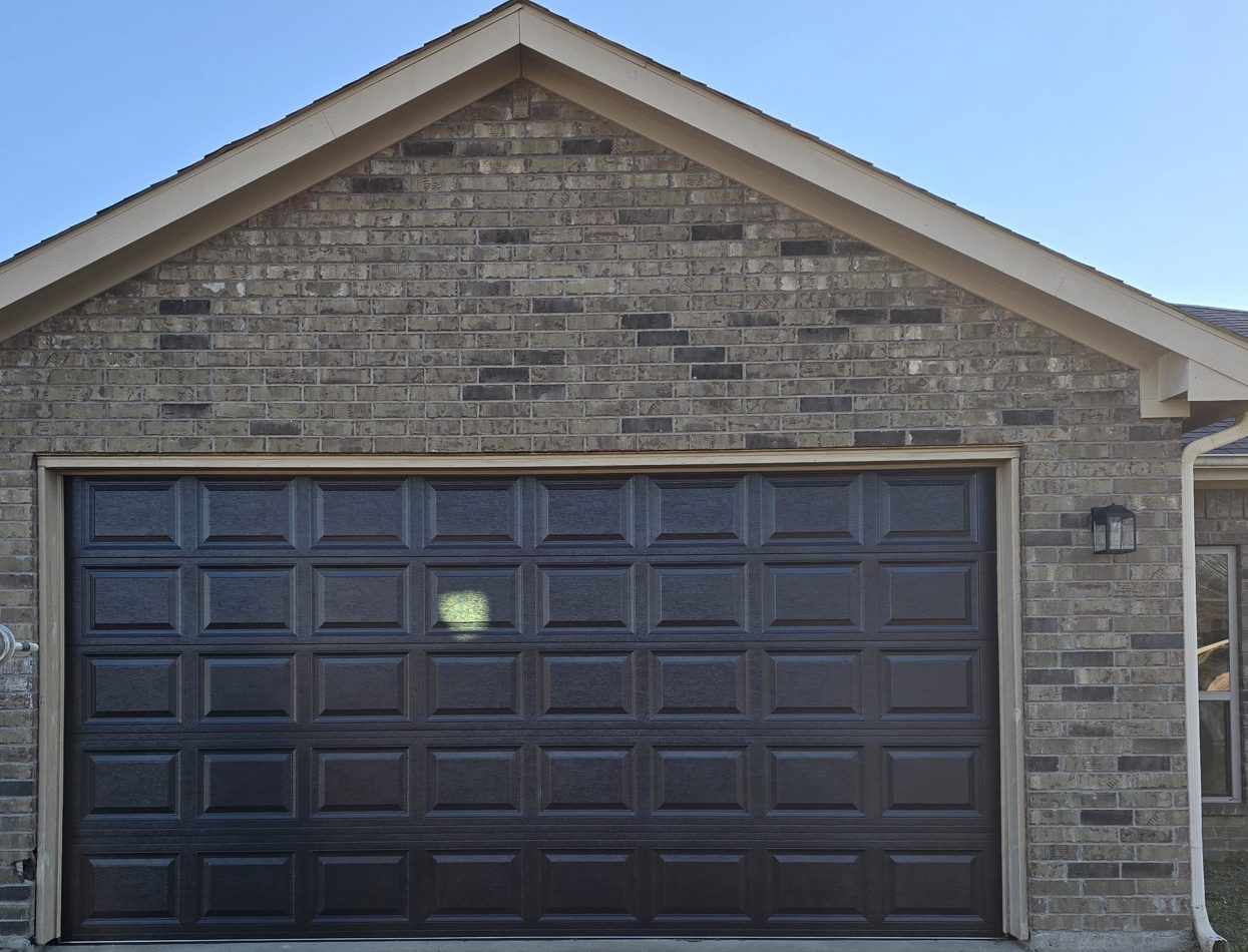 A single dark raised-panel garage door installed on a home