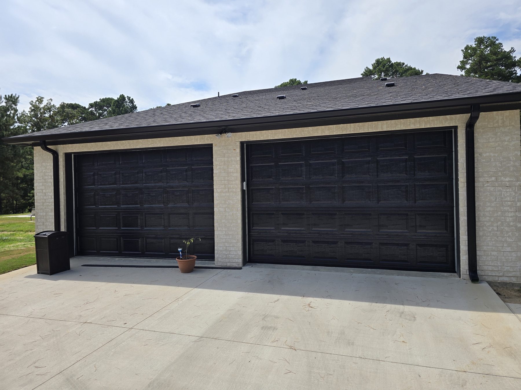 Two dark carriage-style garage doors on a brick building