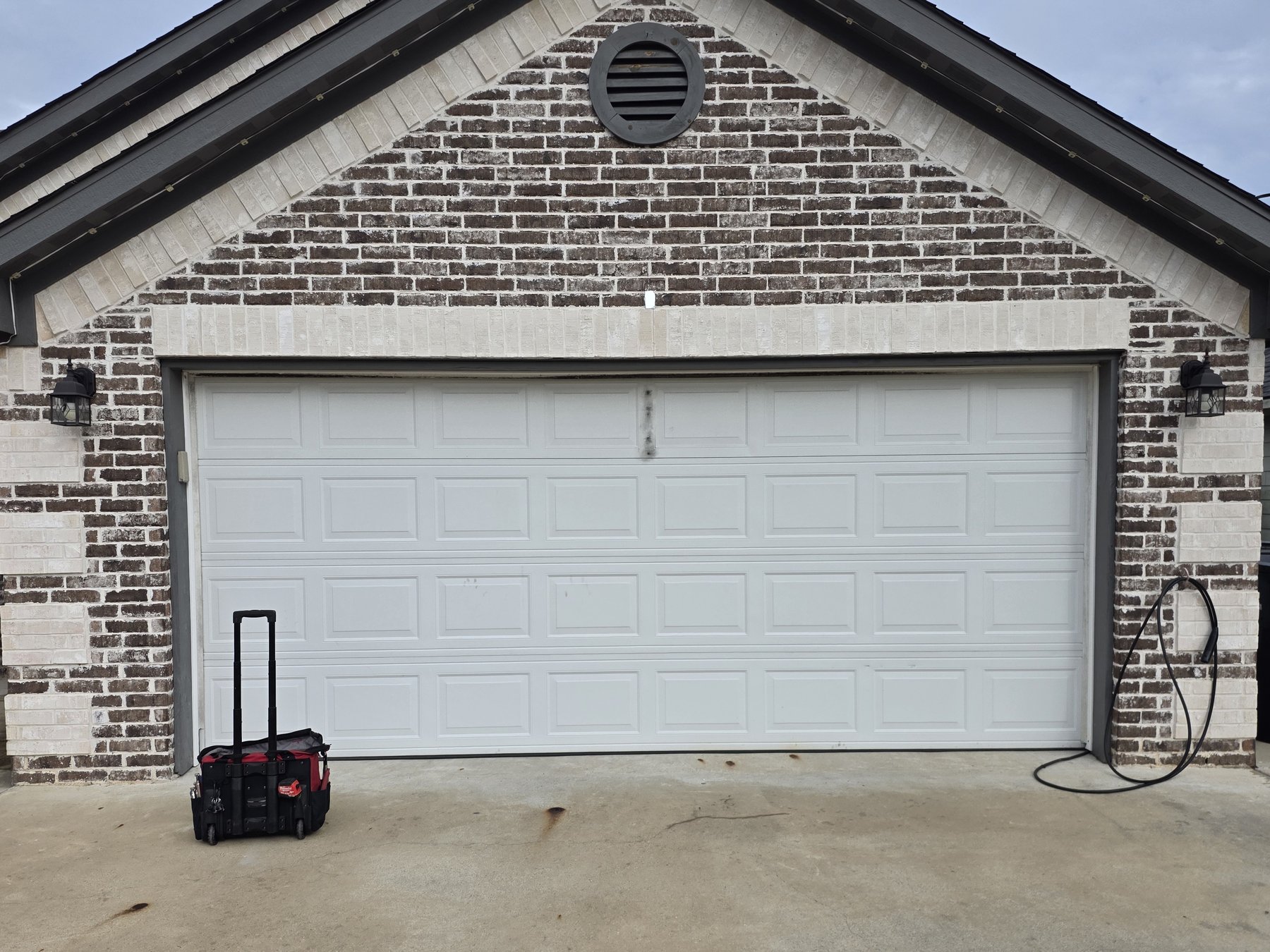 After: the same brick house with the white garage door back on track